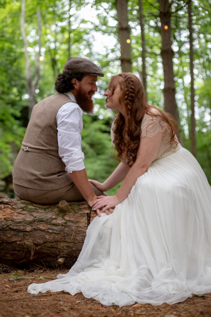 Bride and groom sitting on log in forest – Akron wedding photographer candid style