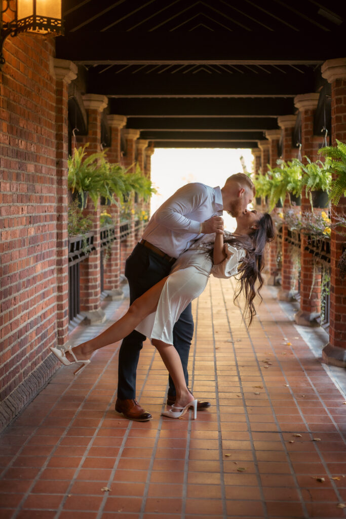 Couple kissing under covered brick walkway at Stan Hywet Hall in Akron for engagement shoot.