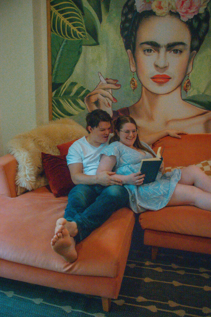 Newly engaged couple planning wedding together on couch with notebook