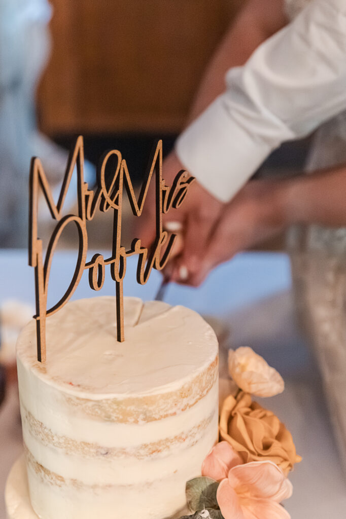 Close-up of the wedding cake cutting with a Mr and Mrs Poore cake topper at Himelright Lodge