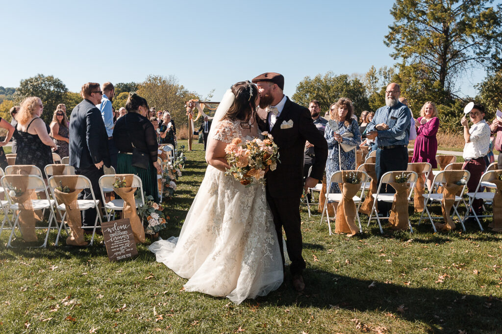 Newly married couple kissing during the outdoor ceremony recessional at Himelright Lodge in Akron, Ohio